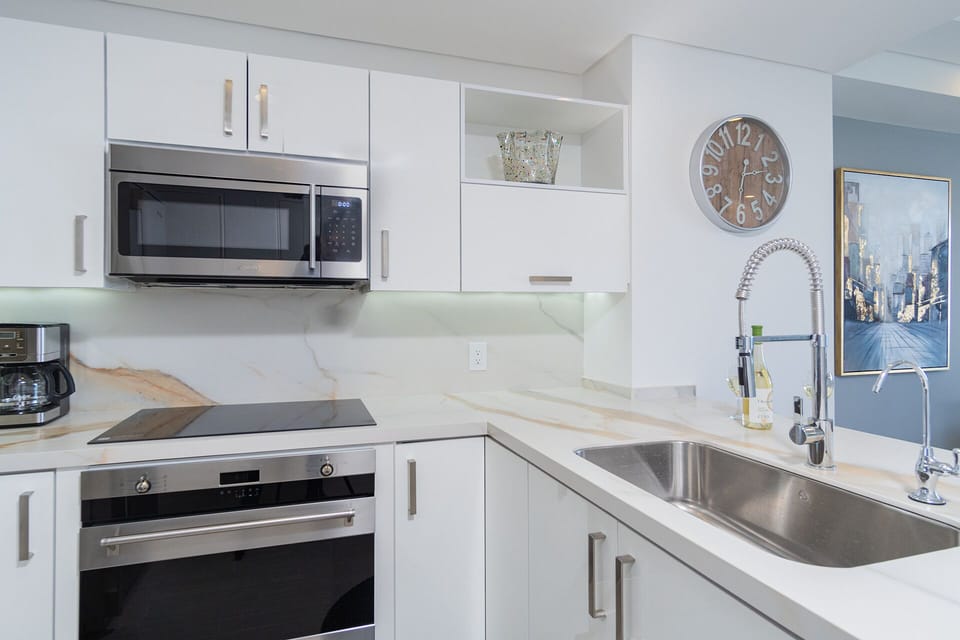 Detail of the kitchen with its new modern appliances like the sink, stove, and microwave.
