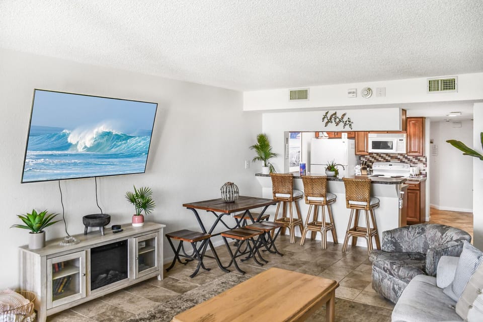 Modern living space with a large TV and open kitchen.