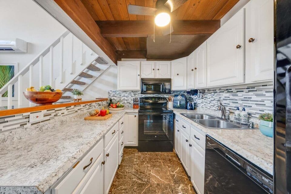 Bright galley kitchen with full appliances, wood ceiling, and ample storage.