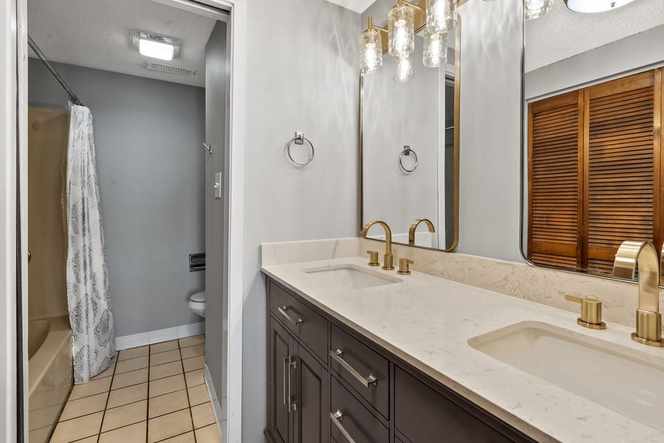 Bathroom with double sinks, gold fixtures and a shower at Sedgefield 403 in Cherry Grove