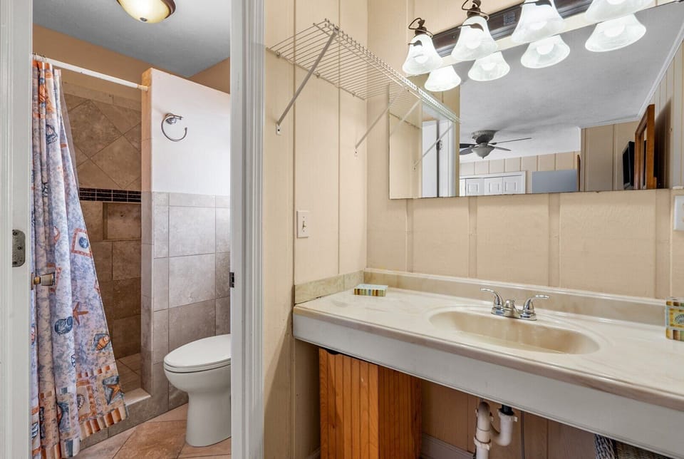 Bathroom with a curtained shower, vanity and lit mirror at See the Dunes, a Cherry Grove vacation rental