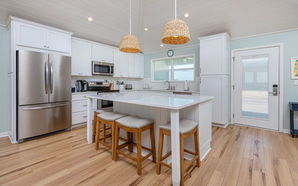 This stylish kitchen features sleek stainless appliances, a spacious island with seating, and a bright, welcoming atmosphere