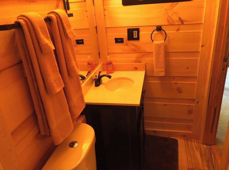 Loft full bathroom with stand-up shower, sink, toilet, towels and soaps 