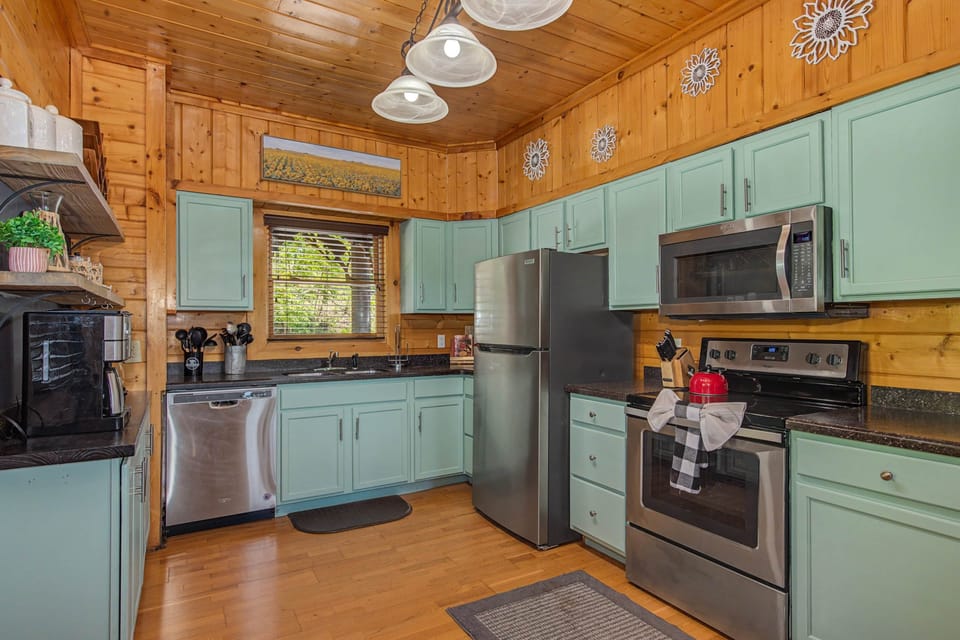 Fully equipped kitchen with green cabinets and stainless appliances