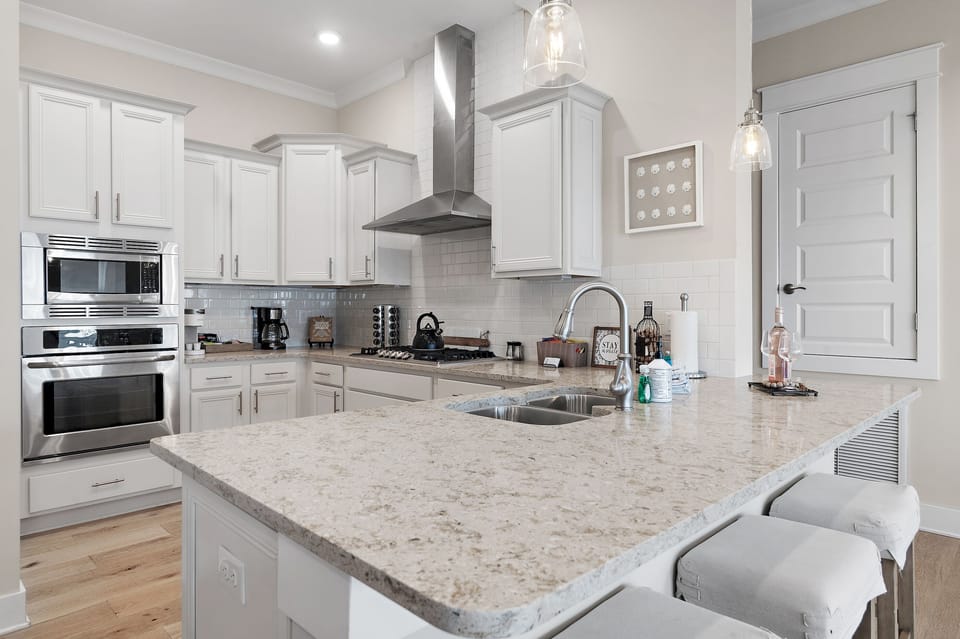 Modern kitchen with quartz island & stainless appliances, liberal counter space.