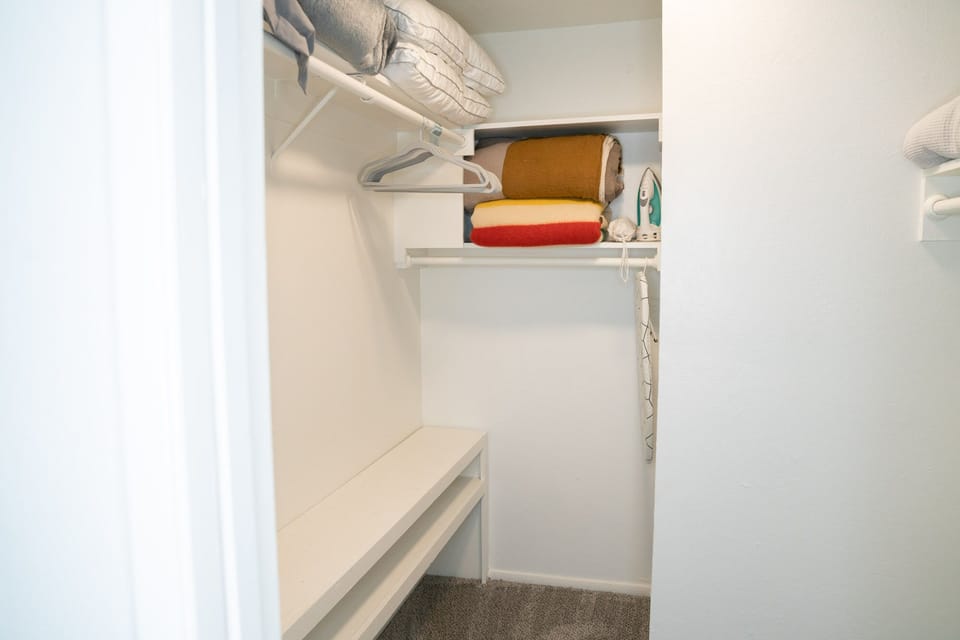 Extra blankets, pillows, an iron and a steamer in the primary bedroom's walk-in closet