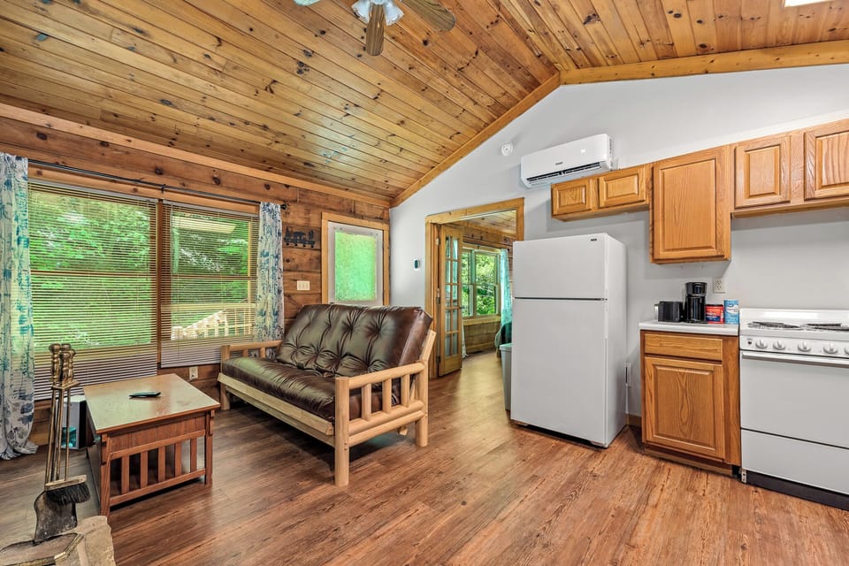 The open living space blends comfort and convenience with wood interiors, a futon sofa, and easy access to kitchen and outdoor areas.