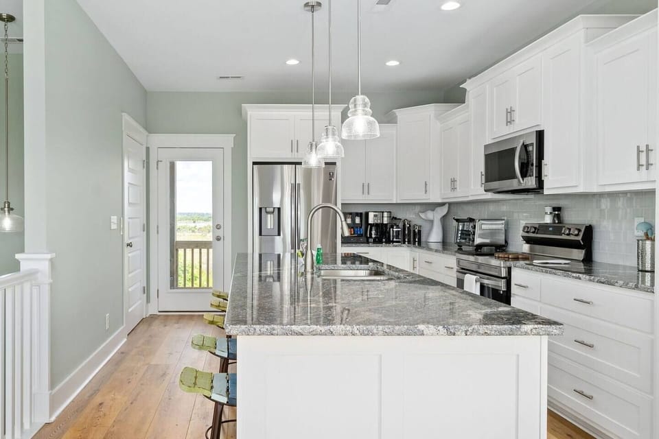 Sophistication meets Functionality: The expansive island accommodates 5 guests, while the kitchen, accessible through the Elevator or stairs, leads to backdoor bliss with stunning sunset views!
