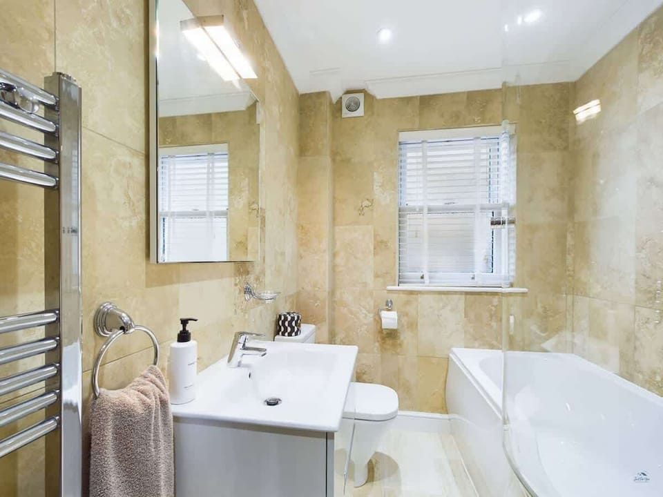 The main family bathroom includes a full-sized bathtub with a shower over and modern vanity.