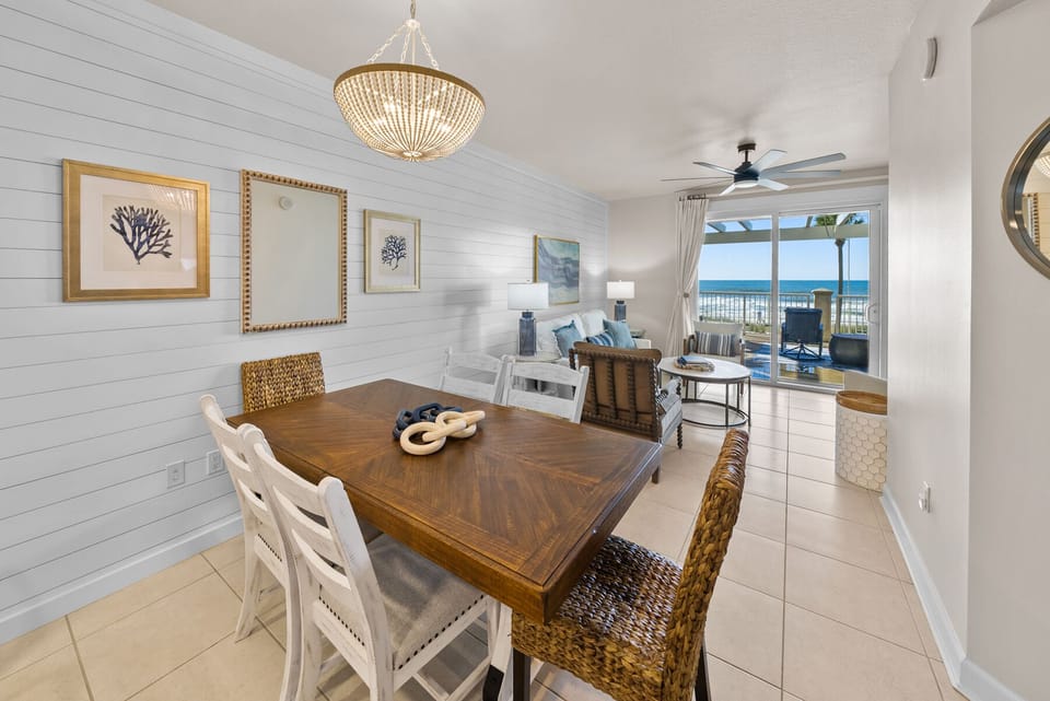Gather around your elegant dining table, where golden chandeliers cast warm light as ocean views frame every meal through expansive windows.