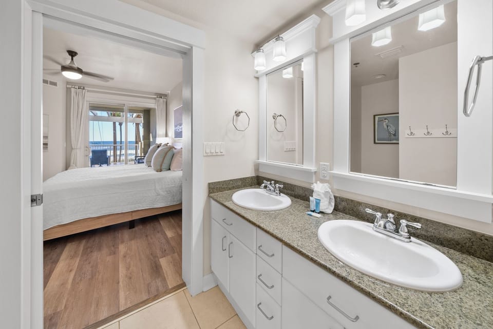 Your ensuite bathroom features dual vanities with granite countertops and bright vanity lighting, perfectly connected to your coastal bedroom.