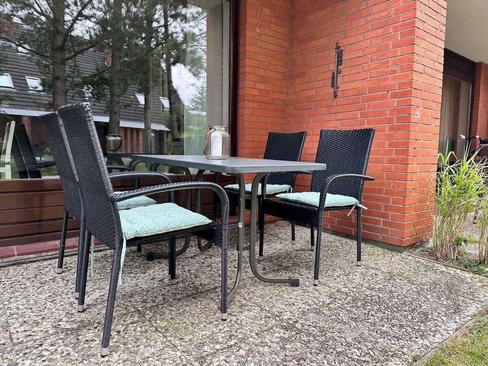 Esstisch mit vier Stühlen und Auflagen auf der überdachten Terrasse. 
