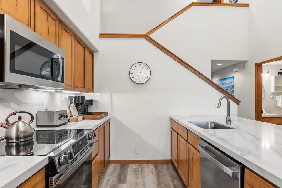 Your fully equipped kitchen features modern appliances, sleek marble countertops, and warm wood cabinetry—everything you need to whip up meals or brew morning coffee in style.