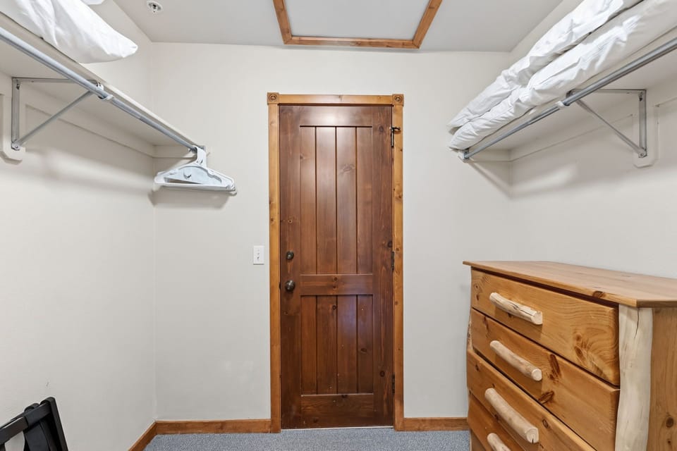 Unpack with ease in your thoughtfully designed closet space featuring dual hanging rods with fresh linens, a charming wooden dresser for extra storage, and warm wood accents that blend rustic style with modern convenience.