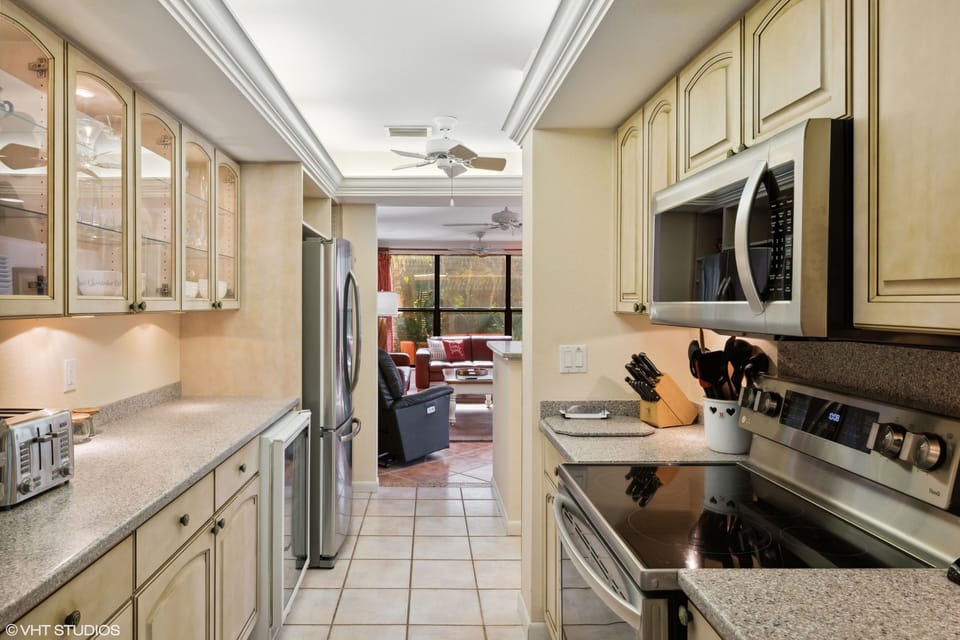 Upgraded kitchen with Corian counters, glass cabinets, and tray lighting.