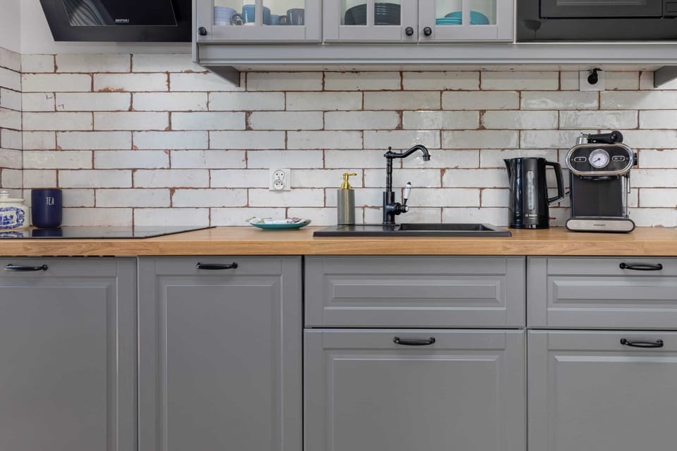 A small kitchen setup with white subway tiles, grey cabinets, and essential appliances like a coffee maker and toaster.