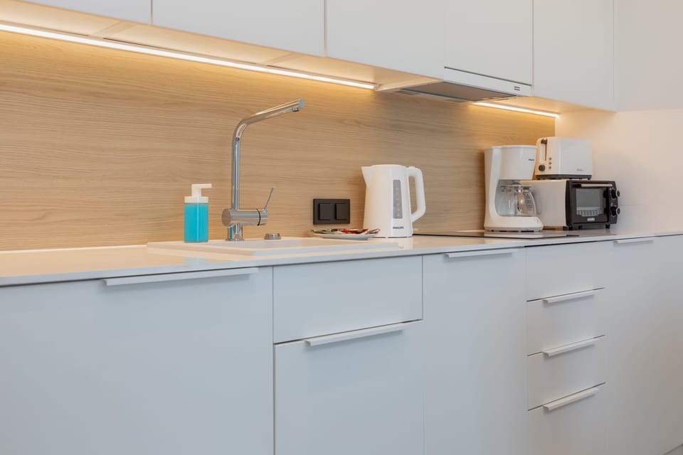A close-up of a kitchen setup with under-cabinet lighting, a microwave, and a kettle for convenience.