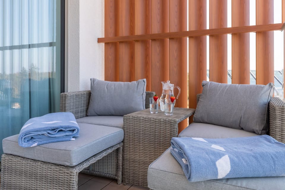 A balcony setup with two rattan chairs, a small table, and a beautiful view, perfect for relaxation.