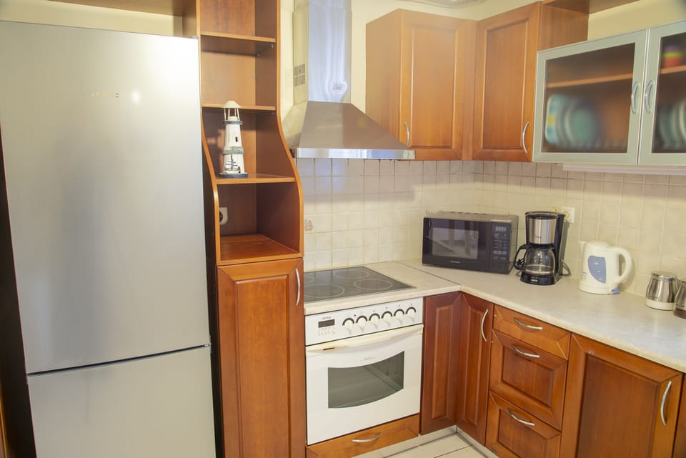 Fully equipped kitchen with stove, oven, fridge, coffee machine, and kettle.