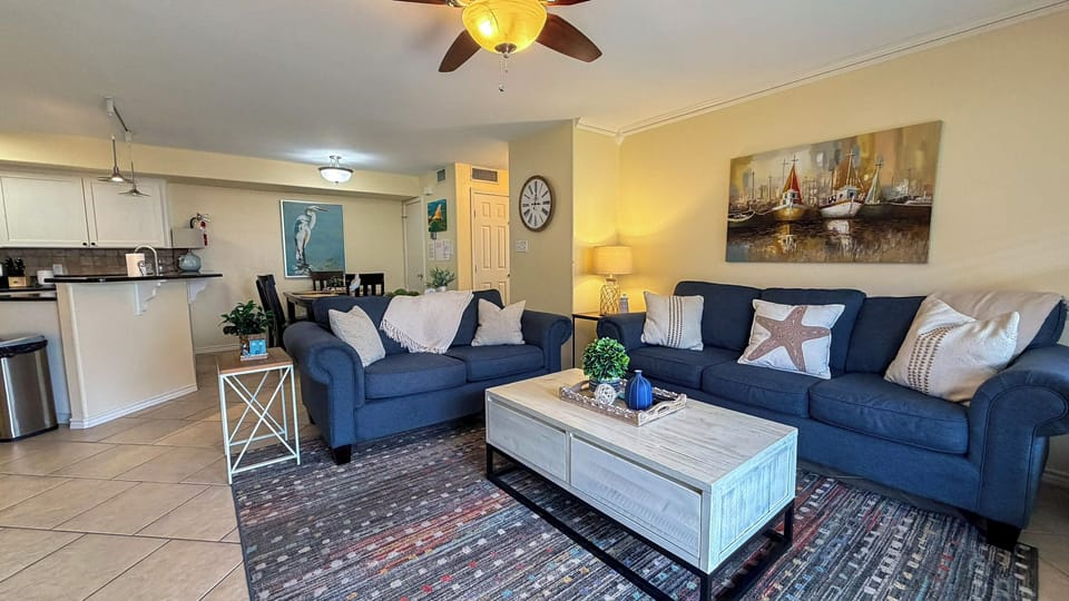 Unwind in your coastal-themed living room with plush navy sofas and open kitchen - perfect for relaxing after beachside adventures.