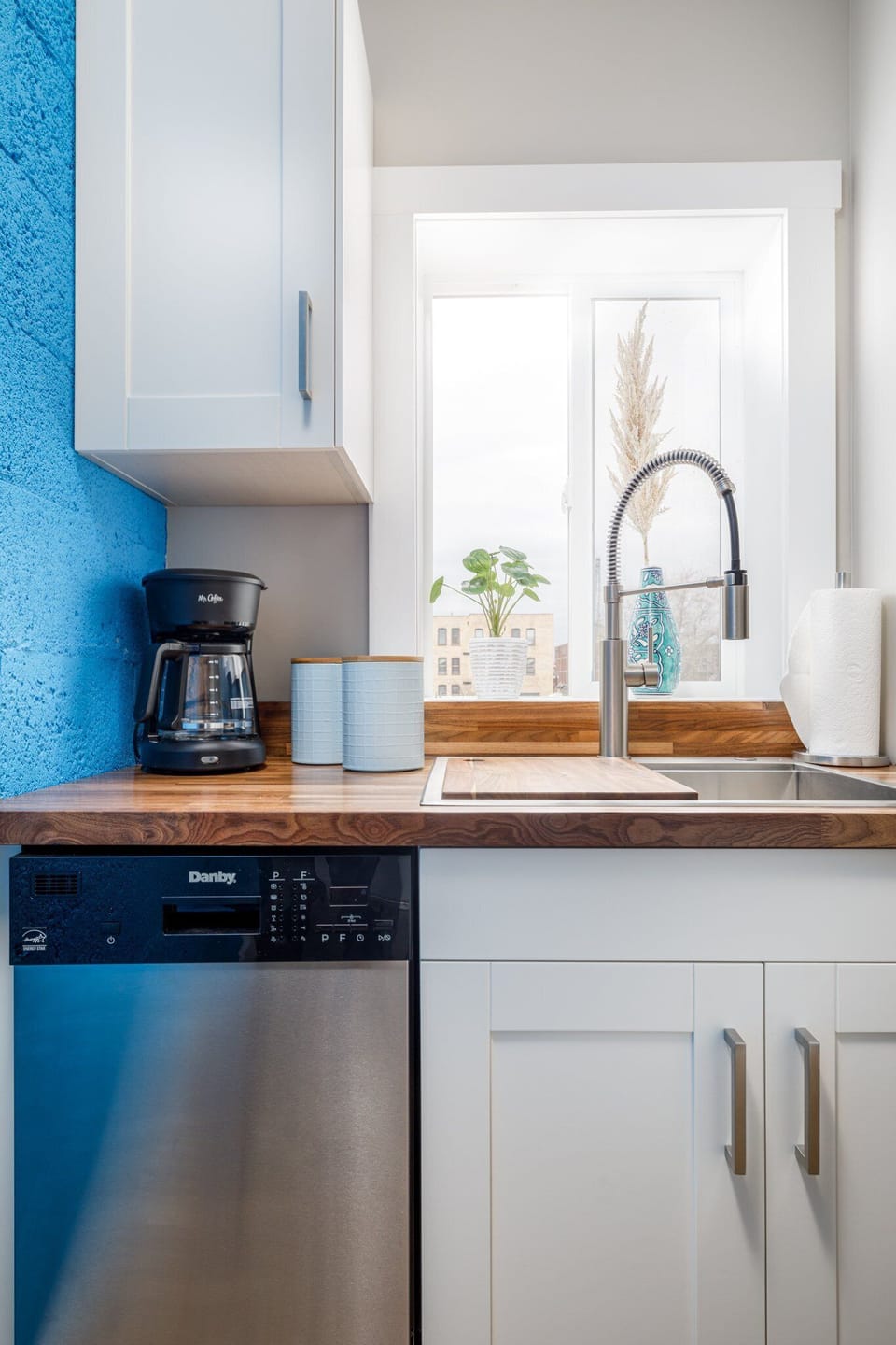 Charming coffee station by the sink w/ blue tile backsplash & window light for slow mornings.