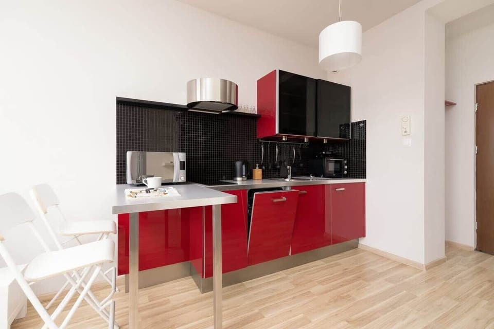A kitchen with red cabinets, a dining area, and a view into the adjoining living space.