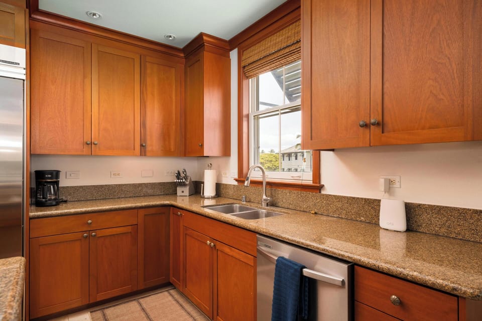 Prepare your favorite meals in this well-equipped kitchen featuring rich wood cabinetry, granite countertops, stainless steel appliances, and a window that fills the space with natural light.