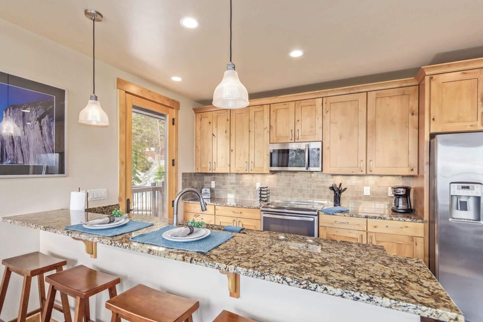 This charming kitchen boasts stainless steel appliances, a convenient bar/serving area with seating for four that connects to the dining room space and access to a patio.
