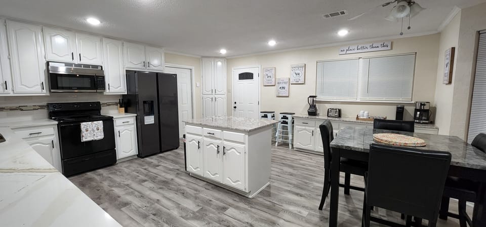 Kitchen with black stainless steel appliances, dining table and iseland.