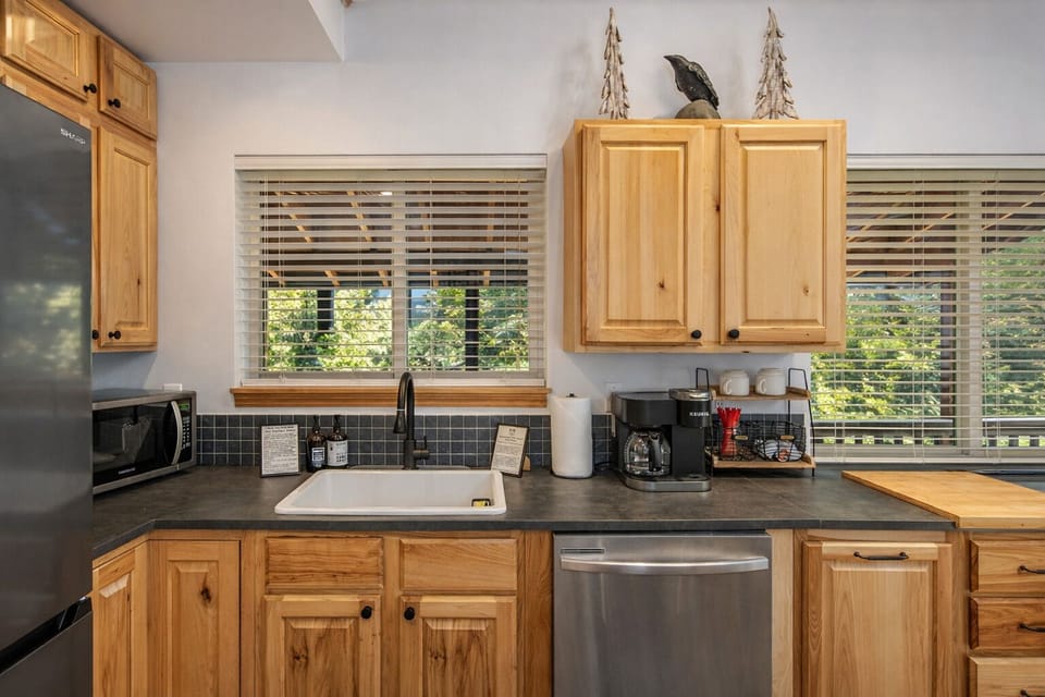 Your fully equipped kitchen awaits with warm wood cabinets, modern appliances, and peaceful garden views through every window.