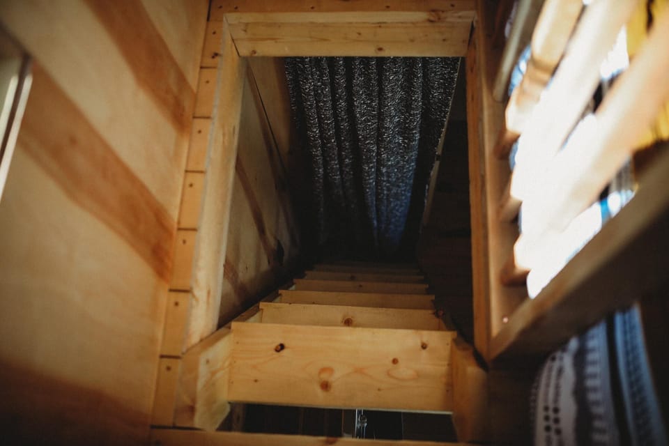 Access your peaceful loft easily with a sturdy wooden ladder, creating an elevated retreat in your Alaskan treehouse.