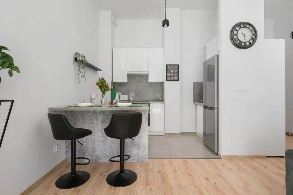 A compact kitchenette with a countertop and two modern black bar stools. The setup is functional and stylish.