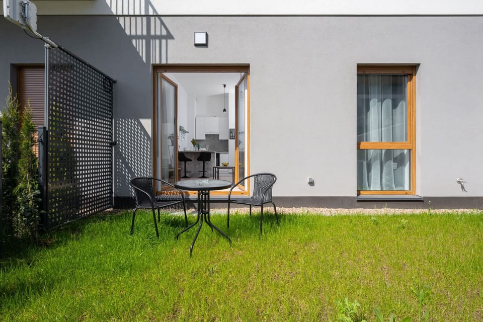 Another angle of the grassy yard with a small seating area. Large windows connect it to the indoor space.