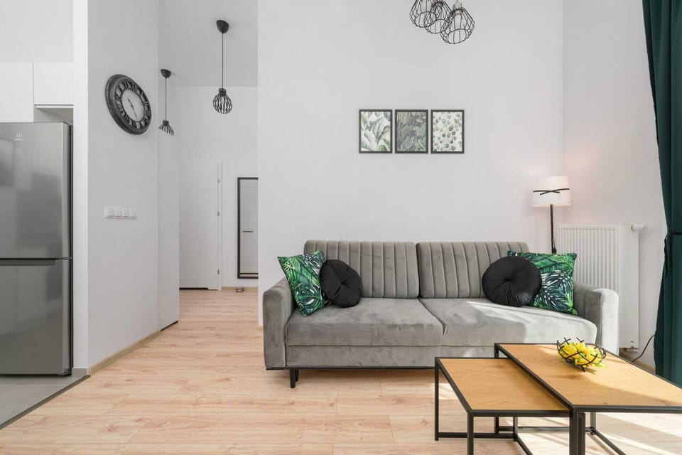 Another angle of the living room with a similar sofa and decor. Large windows with green curtains add a fresh vibe.
