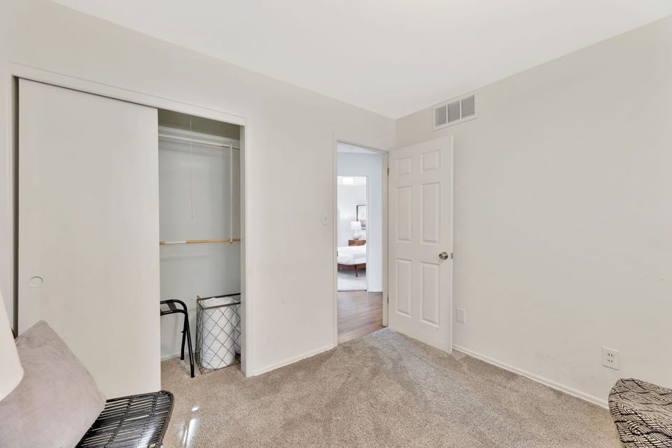 Cozy guest room with closet storage and plush carpet, bright and clean