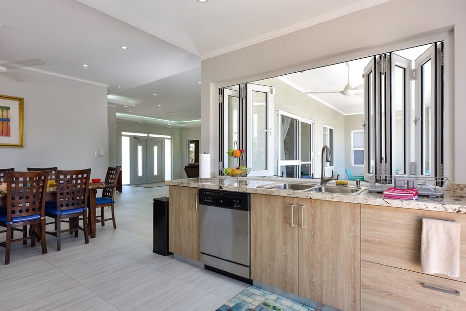 Kitchen with open windows to the outside deck; open concept; dishwasher, sink.