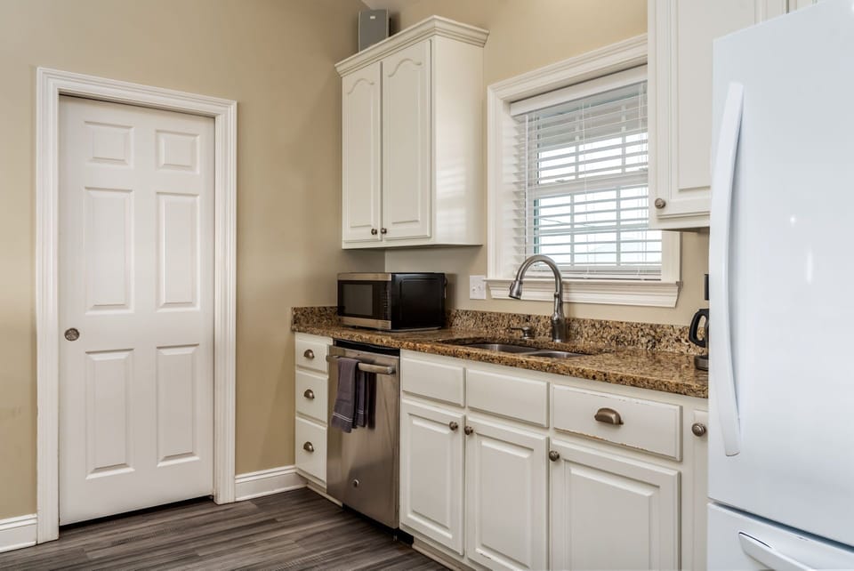 Step into your fully equipped kitchen with granite countertops, white cabinetry, and modern appliances ready for your culinary adventures.