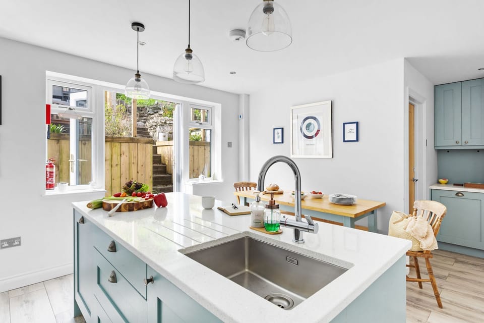 Open plan kitchen/diner, island with sink and door leading to garden - Bumble Cottage