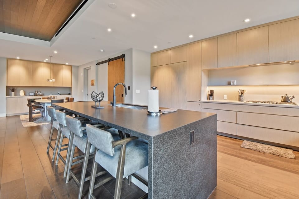 Gather around the sleek island where culinary adventures await. Modern appliances, abundant counter space, and warm wood tones create your perfect home-away-from-home cooking experience.