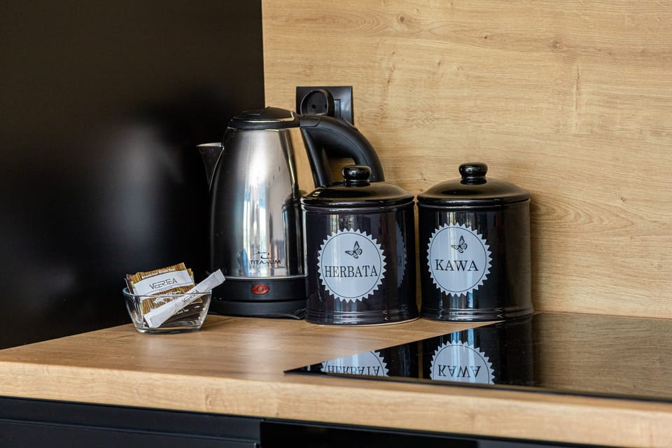 A stylish coffee corner in the kitchen with a variety of cups and a modern kettle. The wooden countertop adds warmth to the sleek black cabinetry.