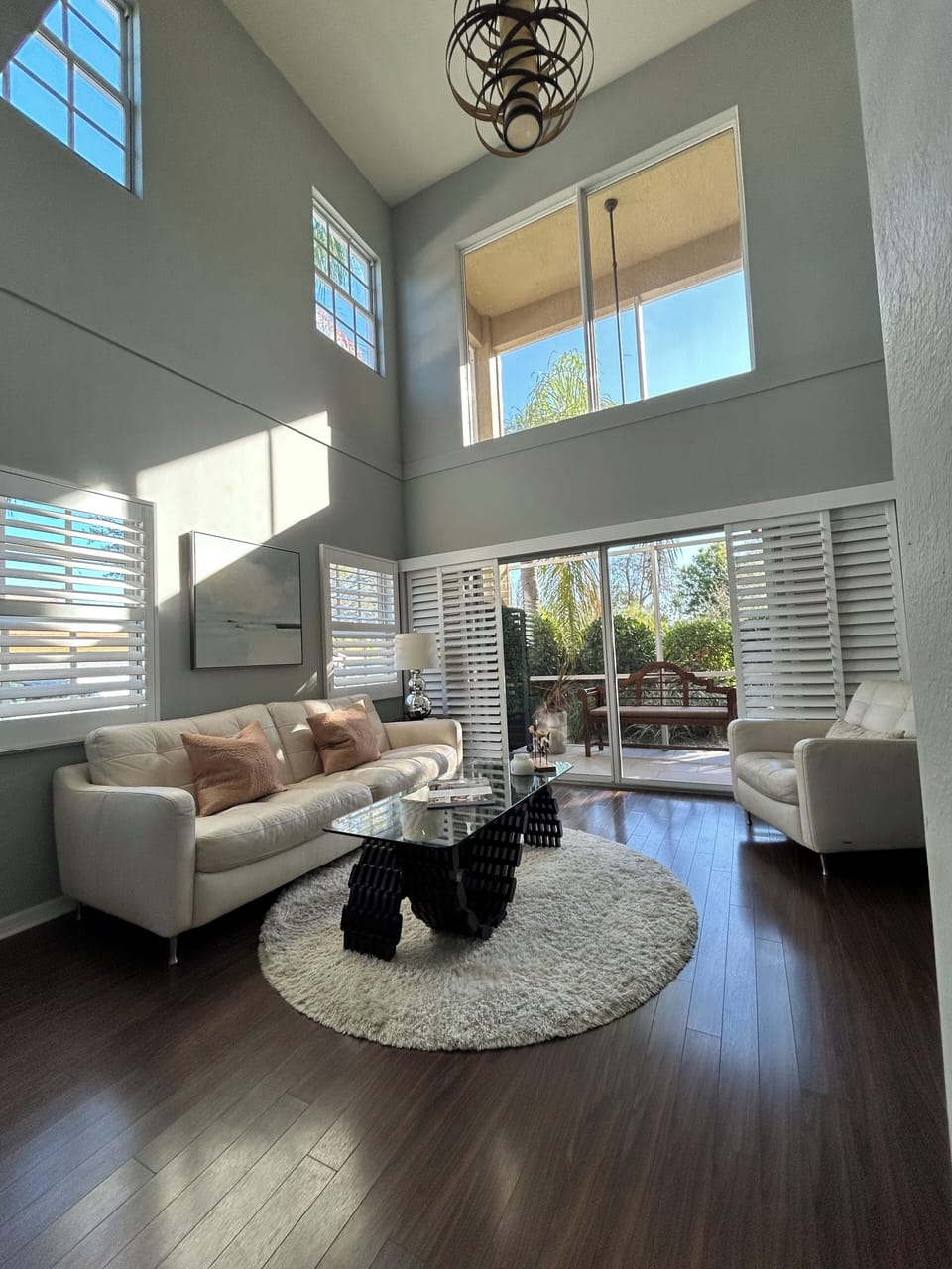 Light-filled living area featuring 20’ ceilings and garden views