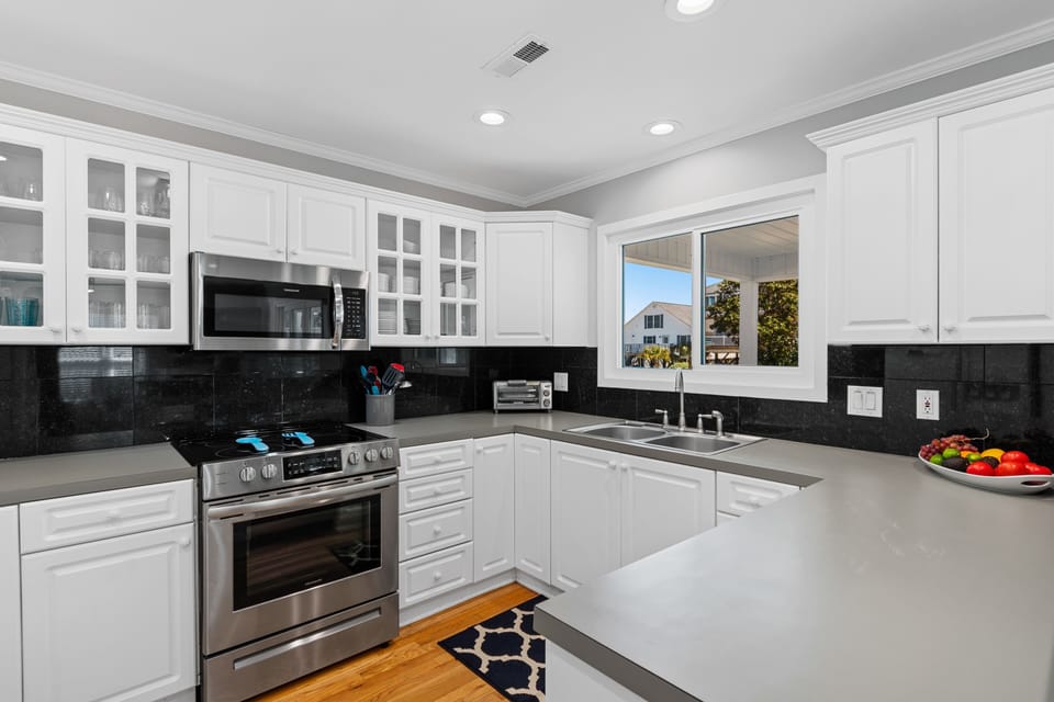 Your spacious kitchen features sleek white cabinets, granite counters, and modern appliances perfect for creating memorable meals during your stay.