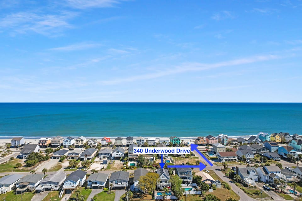 Aerial view of 340 Underwood Drive in a charming beachfront neighborhood with colorful coastal homes and pristine ocean access.