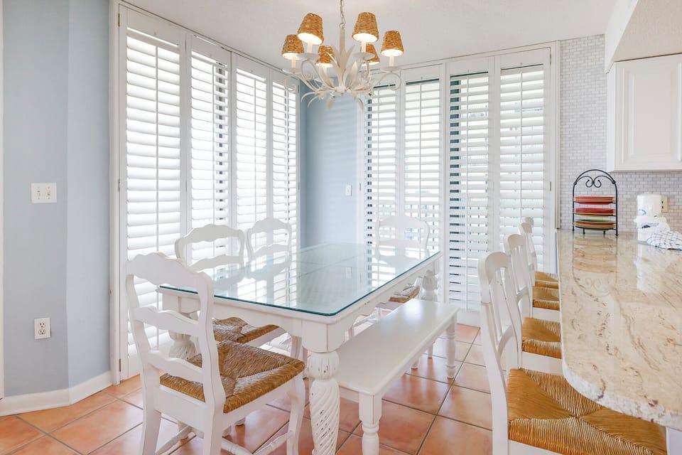 Gather around the spacious glass dining table, surrounded by natural light and charming decor for memorable meals
