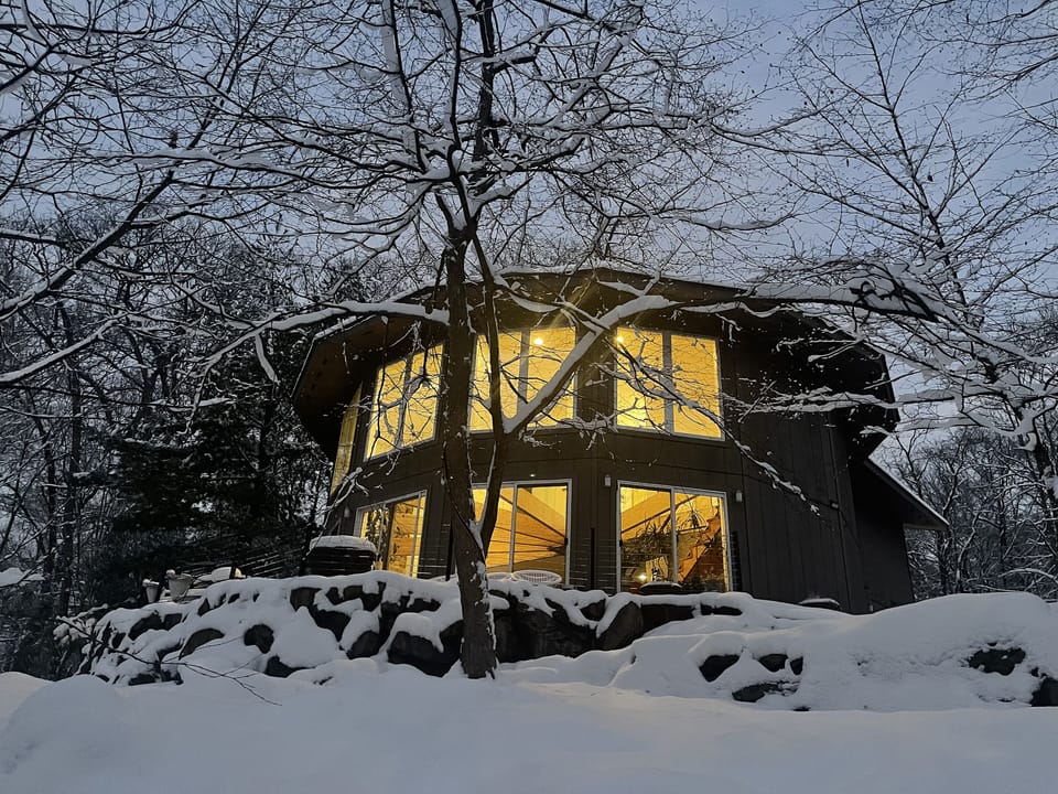 Lodge- Winter lake view with house aglow and snowy trees at dusk