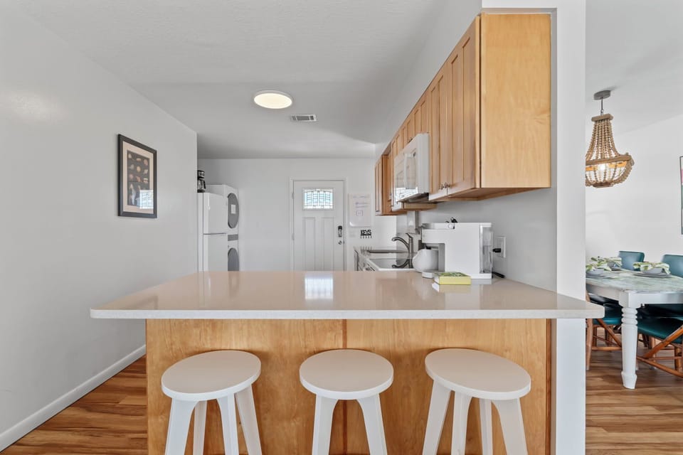Another angle of the sunny kitchen shows how it flows into the adjoining dining space—perfect for gathering your family and friends. The table seats up to 8, setting the stage for shared meals, meaningful conversations, and lasting vacation memories.