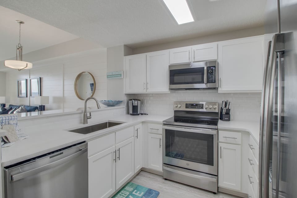 Kitchen features a full size fridge / freezer + dishwasher + stove + microwave + cooking + eating utensils and dishware!