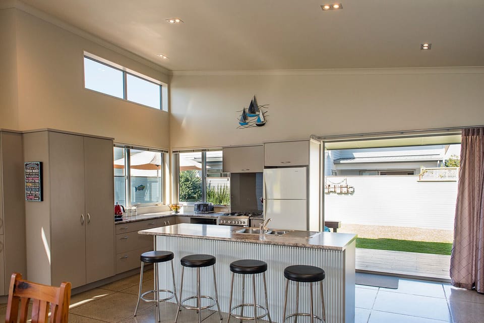 A bright sunny fully equipped kitchen with barstools, perfect for entertaining.