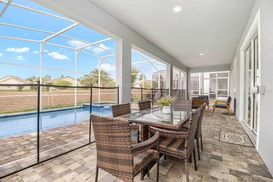 Screened private pool with a covered patio, six-seat wicker dining set, and lounge seating for relaxed outdoor gatherings. (Common Area)