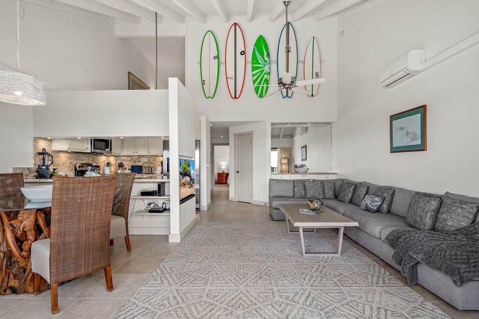 Relax in your spacious coastal retreat with soaring ceilings, a cozy sectional, and beach-inspired décor—surfboards on display remind you that adventure awaits just outside.